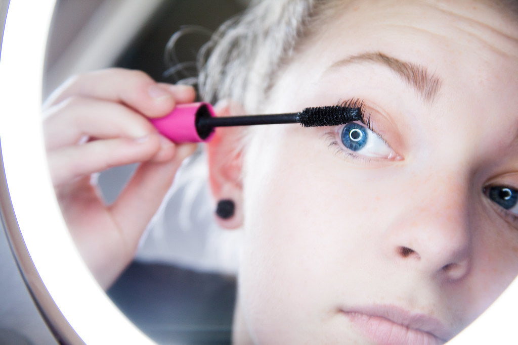 Woman applying hair dye at home without damage using a brush and bowl on clean sectioned hair