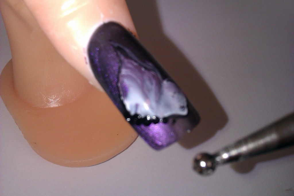 Someone applying best cuticle oil for dry cuticles to their nails with a pen applicator.