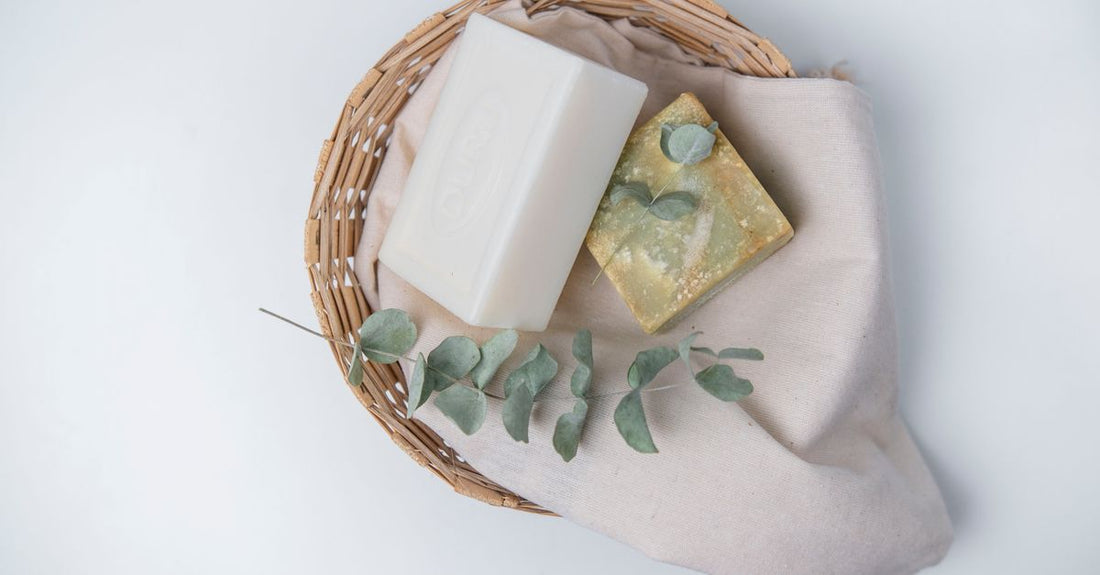 Assorted natural soap bars arranged on a wooden surface with dried botanicals, illustrating how to choose natural soap for different skin types.