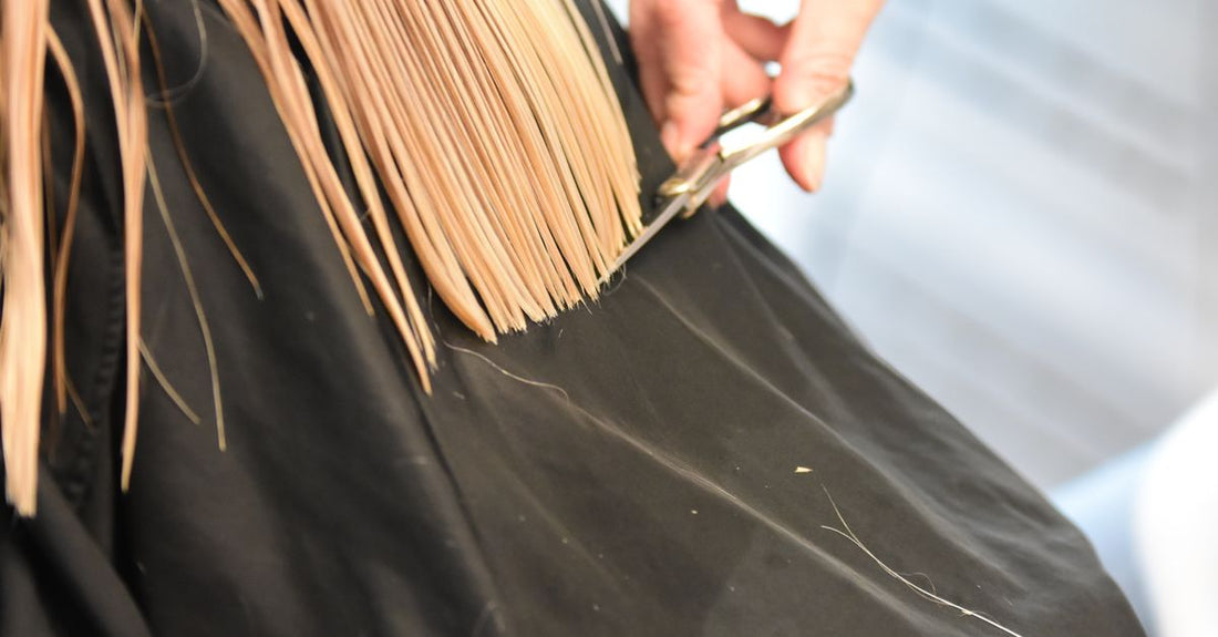 Black waterproof salon cape displayed on a white mannequin, illustrating how to choose capes for salon use.