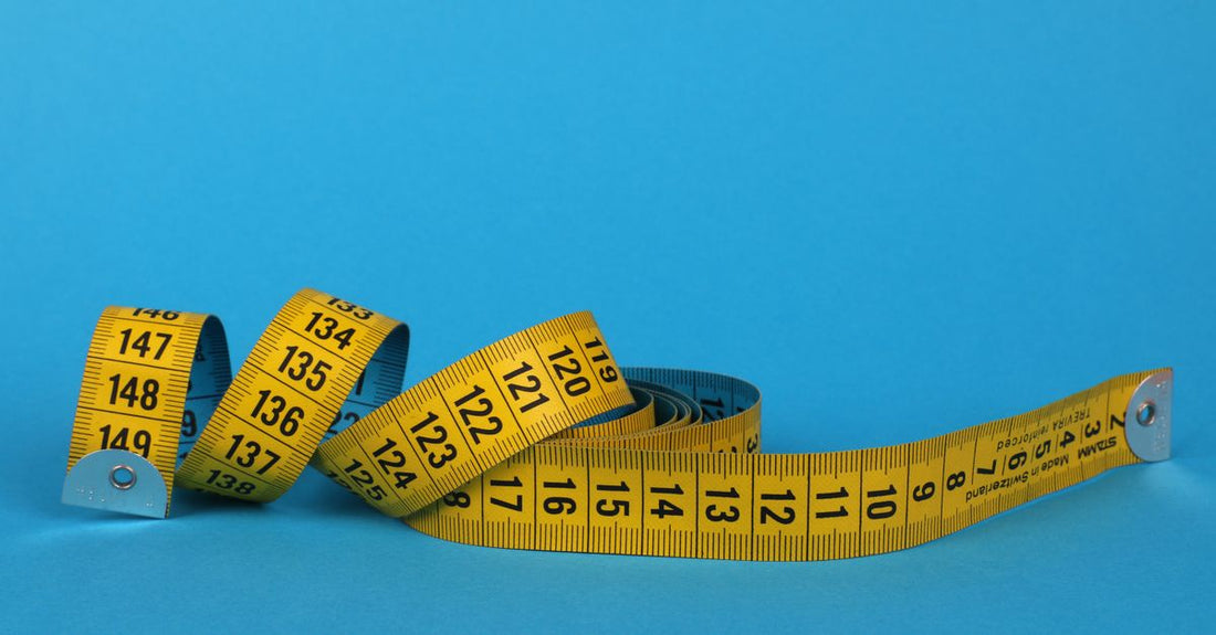 A flexible tailor's tape measure looped around a head circumference, demonstrating how to choose a wig cap size