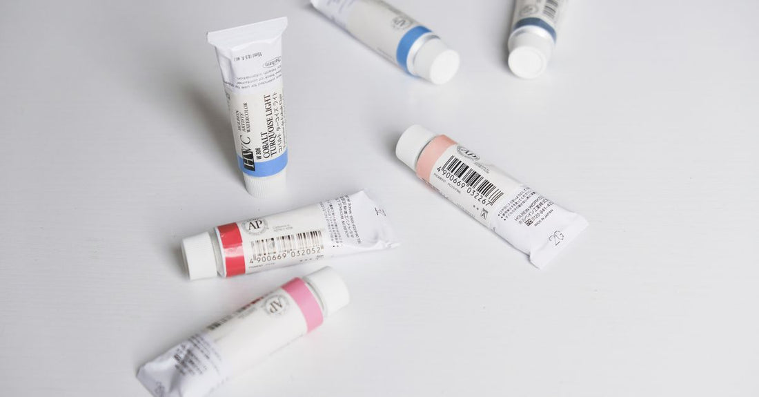 Assorted hair dye tubes and colour swatches for dark hair without bleach laid flat on a white background