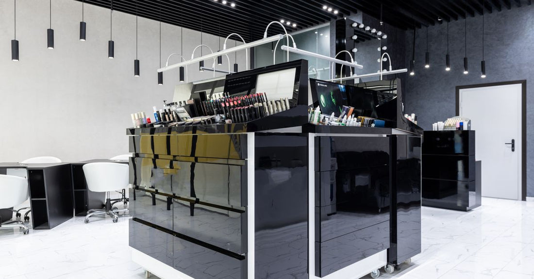 A clear acrylic cosmetic display case with multiple compartments, holding skincare bottles and makeup on a vanity.