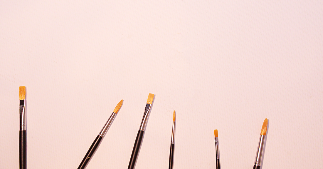 A flatlay of five different eyeliner brushes on a white marble surface, illustrating an eyeliner brushes buying guide
