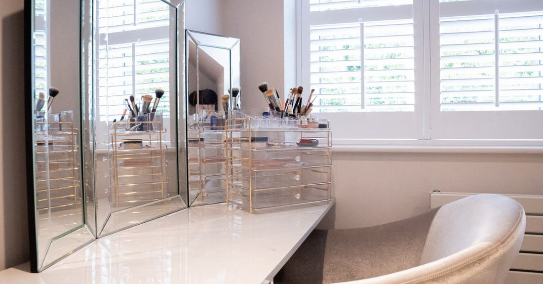 Clear acrylic cosmetic display cases neatly organising makeup brushes and skincare bottles on a vanity counter.