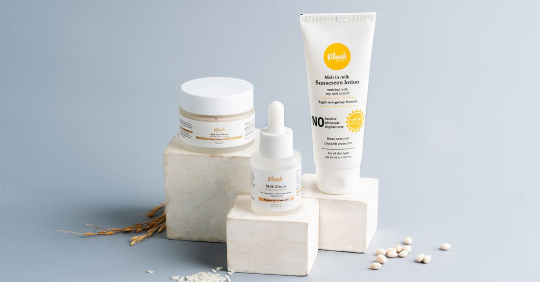 A flatlay arrangement of skincare bottles including toner, serum, moisturiser, and sunscreen on a light marble surface, illustrating how to layer skincare products correctly.