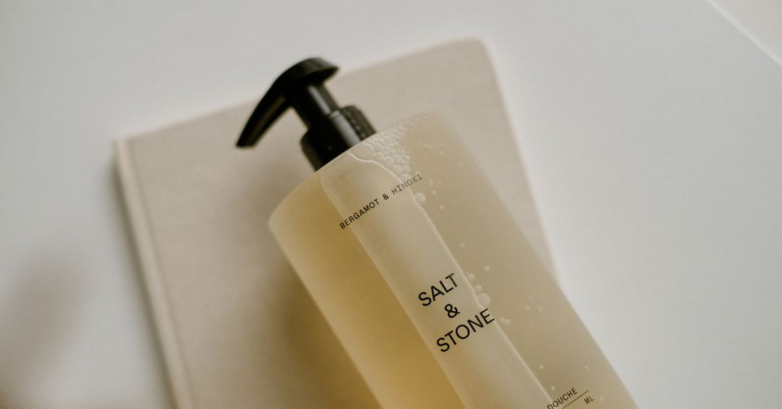 Body washes buying guide UK: an array of body wash bottles on a marble shelf, showcasing different formulas and sizes.