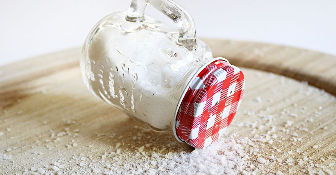 Assorted coloured bath salts in glass jars on a wooden shelf, illustrating a bath salts buying guide for UK shoppers.