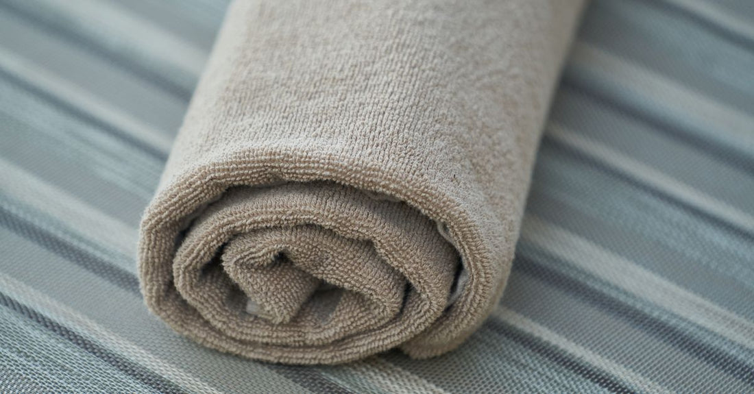 A stack of soft white disposable cotton face towels on a bathroom shelf, best cloths & towelettes 2026 skincare essential.