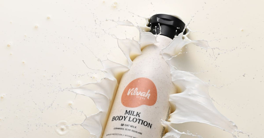 A white body lotion for dry skin UK bottle on a marble surface, with the cream visible beside it.