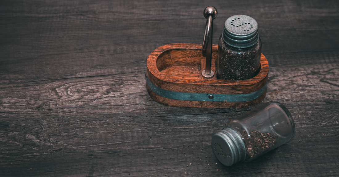 Glass jars of various bath salts including Epsom, Dead Sea, and pink Himalayan, displayed on a wooden shelf — your bath salts buying guide to the right minerals.