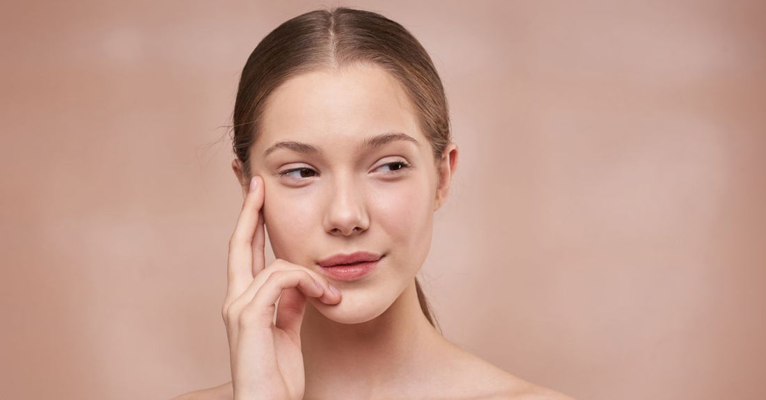 A frosted glass serum bottle on a white marble surface, representing how to reduce pore size with targeted skincare.