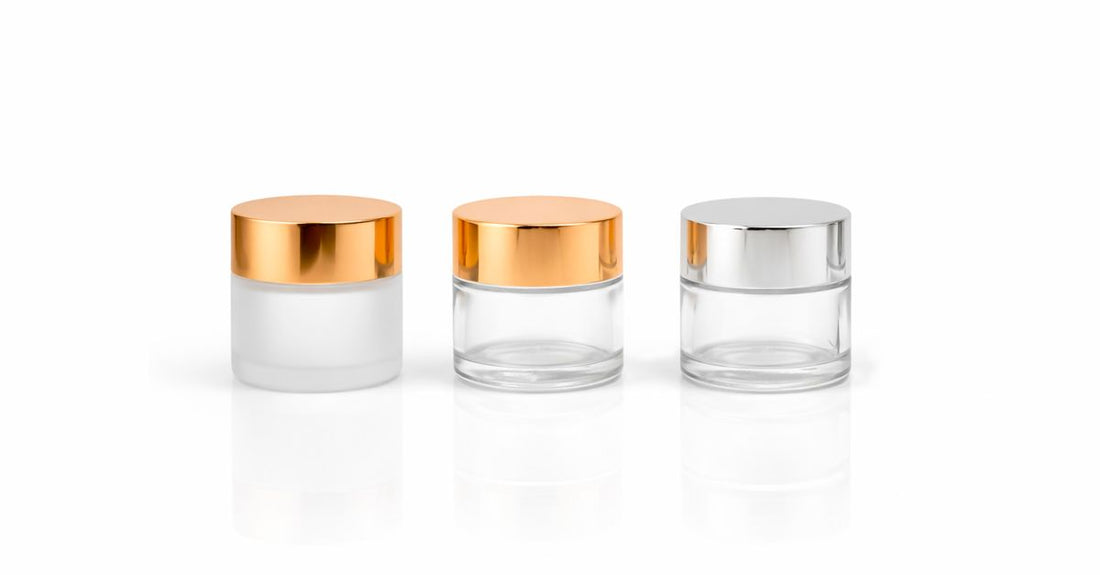 A row of moisturiser jars and face cream pots on a white shelf, illustrating how to choose creams for different skin types.