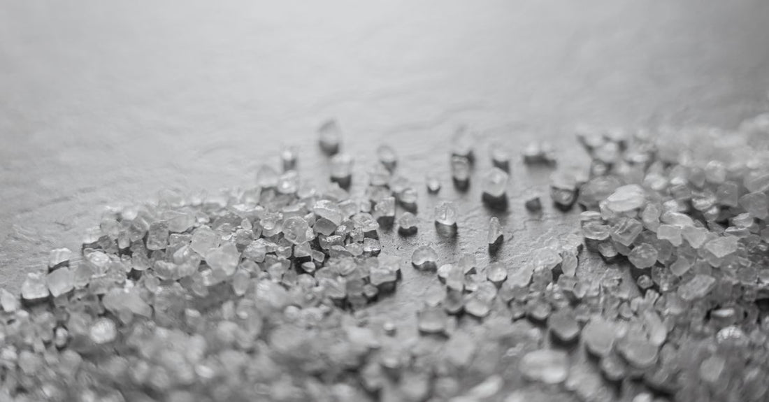 Best bath salts 2026 in a glass jar with a wooden scoop, showing coarse mineral crystals on a light background.