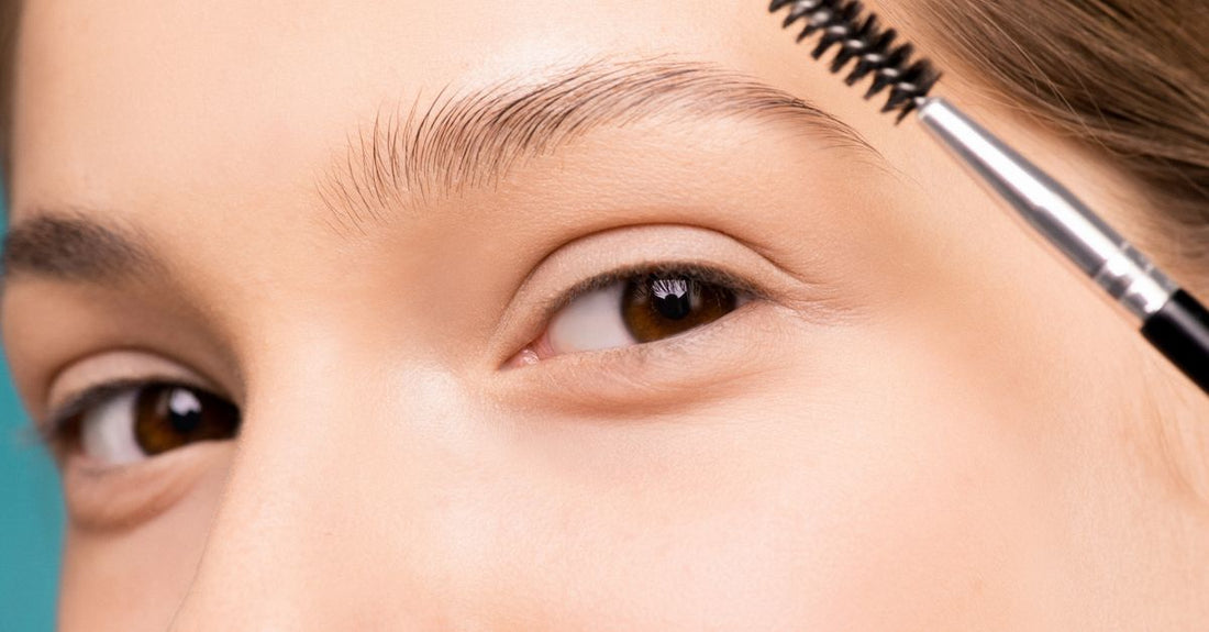 Flatlay of an angled brow brush and spoolie on a clean white surface, demonstrating how to choose brow brushes for precise makeup application.