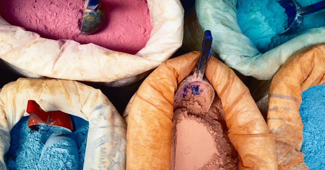 Assorted jars of pure cosmetic colour pigments and filler powders arranged on a white surface, illustrating a color additives & fillers buying guide.