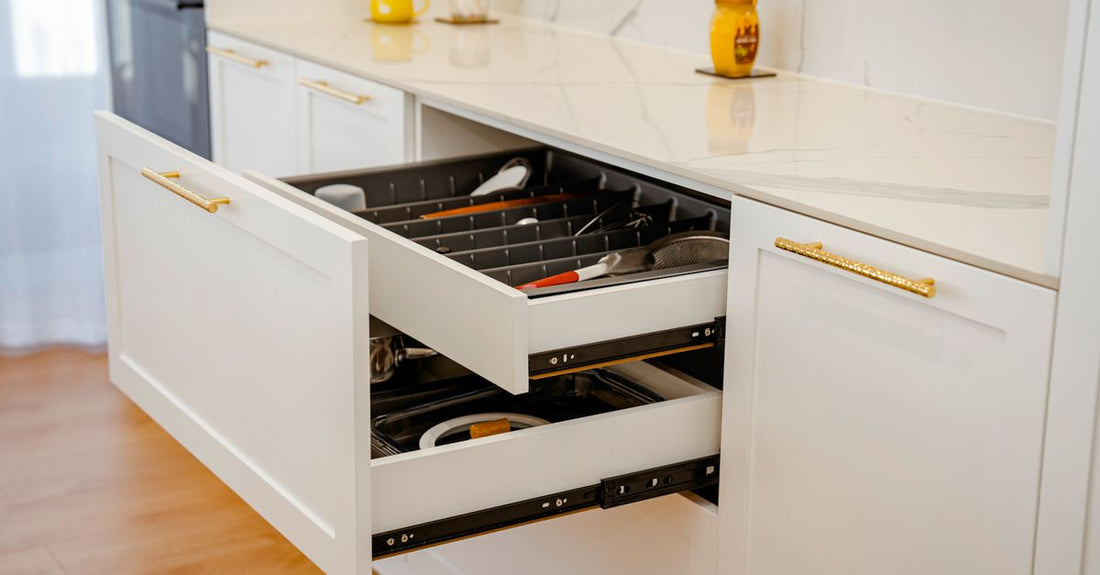 A clear acrylic makeup organiser drawer filled with sorted lipsticks and eyeshadow palettes on a white dressing table — how to organise makeup collection.