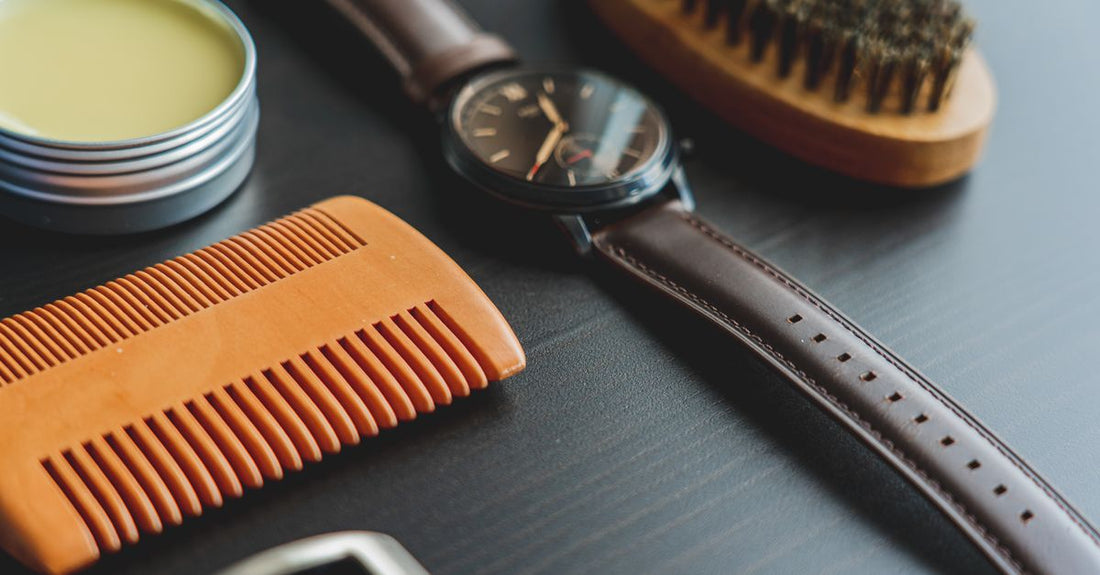 A collection of the best pomades UK 2026 arranged on a dark grooming surface with a comb.