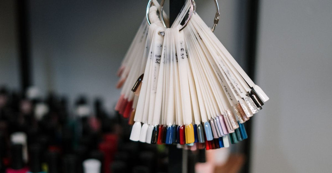 A row of colourful gel polish bottles on a white shelf, illustrating choices in gel polish vs shellac systems.