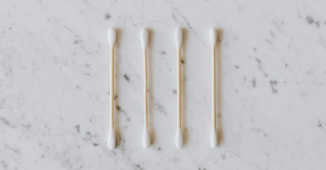 A flatlay of various cotton swabs with wooden and paper sticks, double and pointed tips, on a neutral background. How to choose cotton swabs UK guide.
