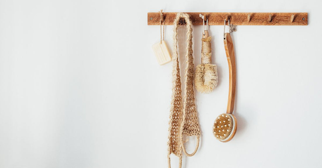 A natural bristle bath and body brush resting on a clean bathroom shelf, illustrating a simple daily skincare routine.