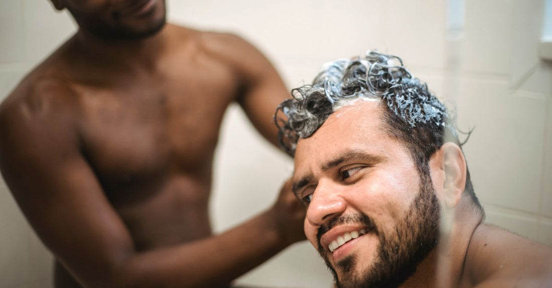 A bottle of beard shampoo on a bathroom shelf with grooming tools, illustrating how to wash beard properly.