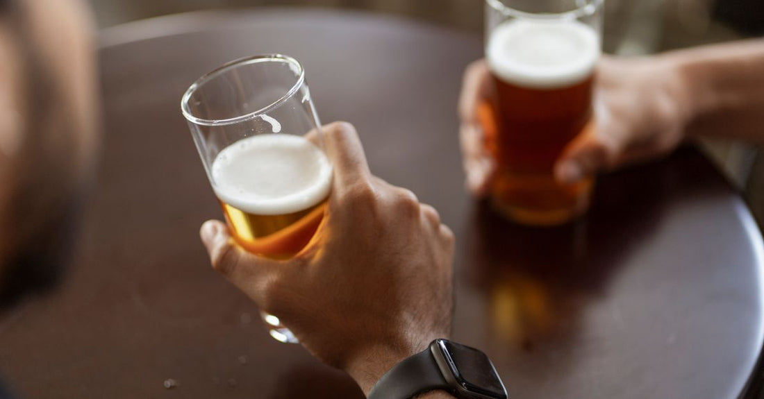 A selection of different beer glasses, including a nonic pint, tulip, and wheat beer glass, arranged on a wooden surface.