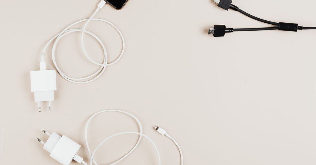 A flatlay of various USB charging cables and small beauty device accessories on a white surface, illustrating how to choose accessories for skincare tools.