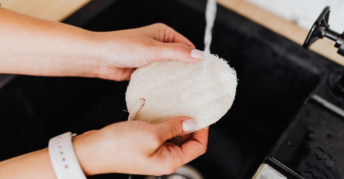 A natural loofah sponge resting on a white bathroom shelf, representing the best loofah for body wash UK.