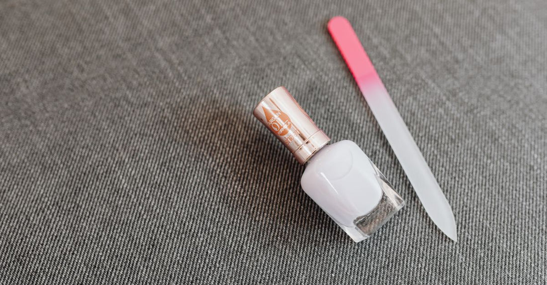 A glass bottle of clear nail base coat on a white background