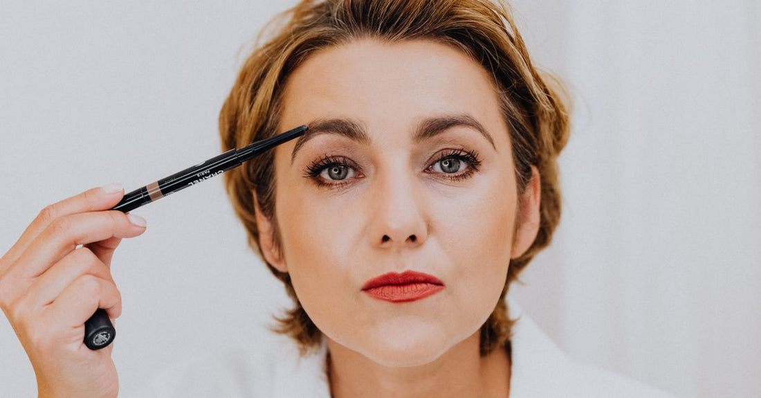 How to choose eyebrow color UK: a row of eyebrow pencil swatches on fair skin showing cool and warm brown shades.