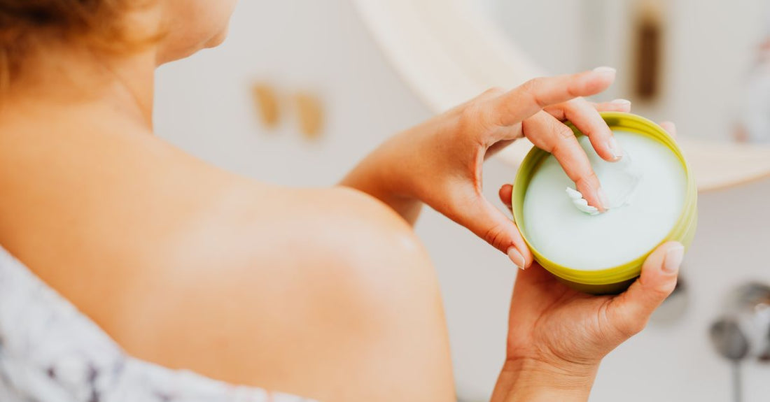 A glass jar of rich, whipped body butter with a wooden scoop, reflecting a natural, luxurious skincare aesthetic.