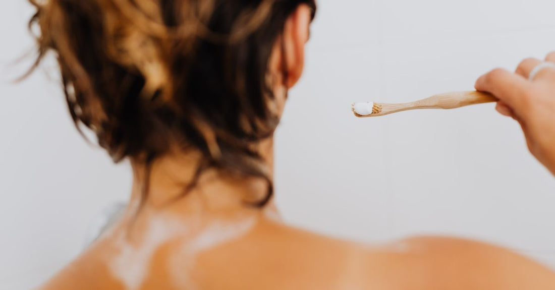 A collection of best bath & body brushes 2026 including wooden dry brushes, silicone scrubbers, and long-handled back brushes arranged on a bathroom shelf.