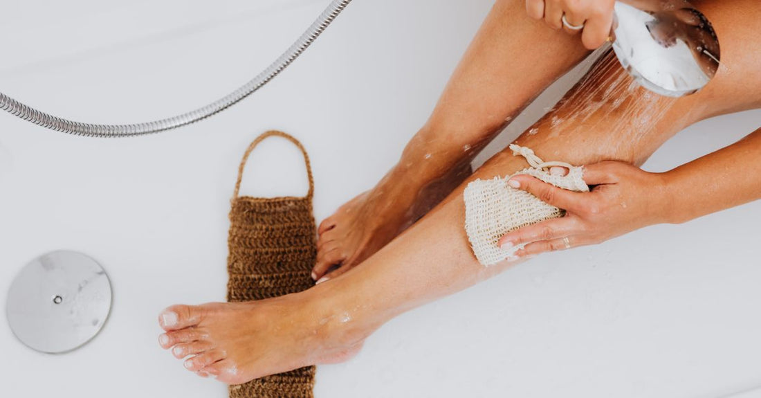 A selection of natural bath sponges including loofah, konjac, and sea wool laid on a light bathroom surface, illustrating how to choose bath sponges for different skin types.