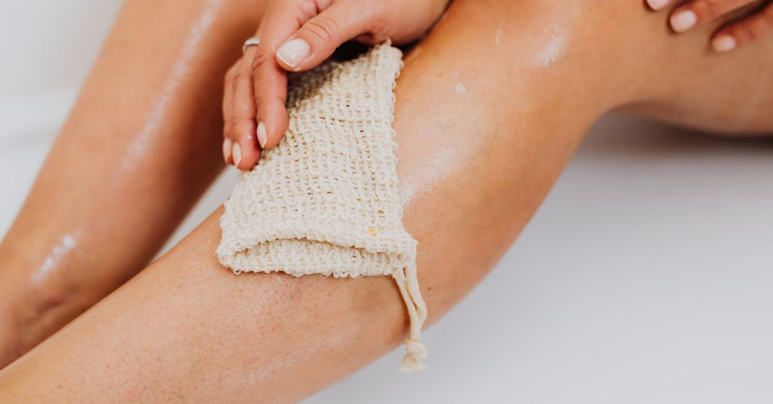 Best loofahs 2026: a clean, white mesh shower pouf and a natural loofah sponge side by side on a white background.