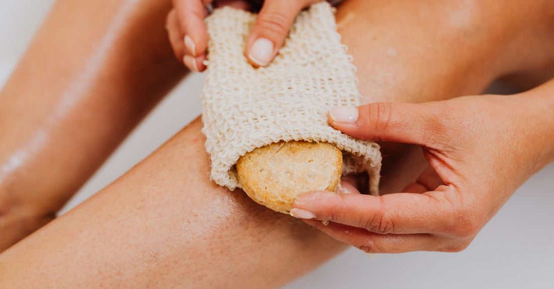 A collection of natural bath sponges including loofah, sea sponge, and konjac sponge on a bathroom shelf, illustrating the best bath sponges 2026.
