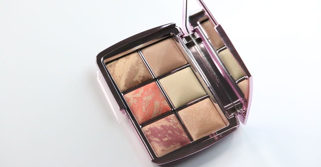 A flatlay of various blusher compacts and palettes in pink, peach, and coral shades, illustrating a blush buying guide.