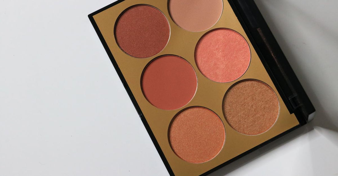 A flatlay of various blush compacts and palettes in pink, peach, and coral shades, showcasing the variety available for how to choose blush.
