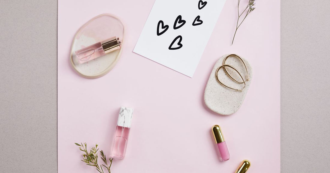Five lip gloss tubes in a row on a white marble surface, showcasing different shades and finishes for a lip glosses buying guide UK.