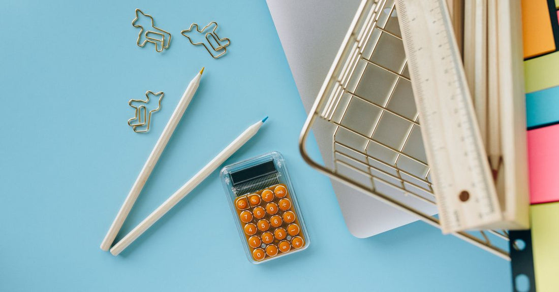 Flatlay photograph of eyebrow pencils and brow gels in neutral brown shades on a marble surface, illustrating how to choose eyebrow color.