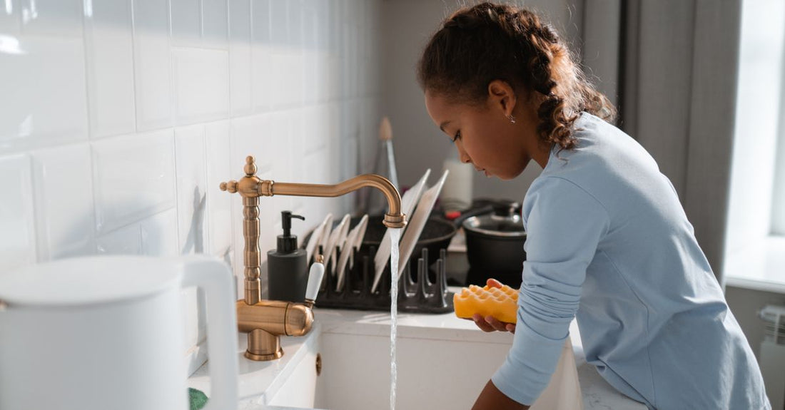 A dishwashing buying guide featuring a clear bottle of dish soap on a kitchen counter, highlighting UK hard water solutions.
