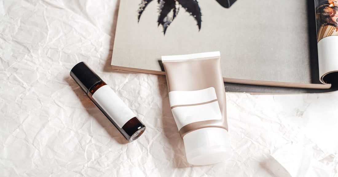 A collection of the best tinted moisturisers UK 2026 displayed on a marble surface with a makeup brush and fresh flowers.