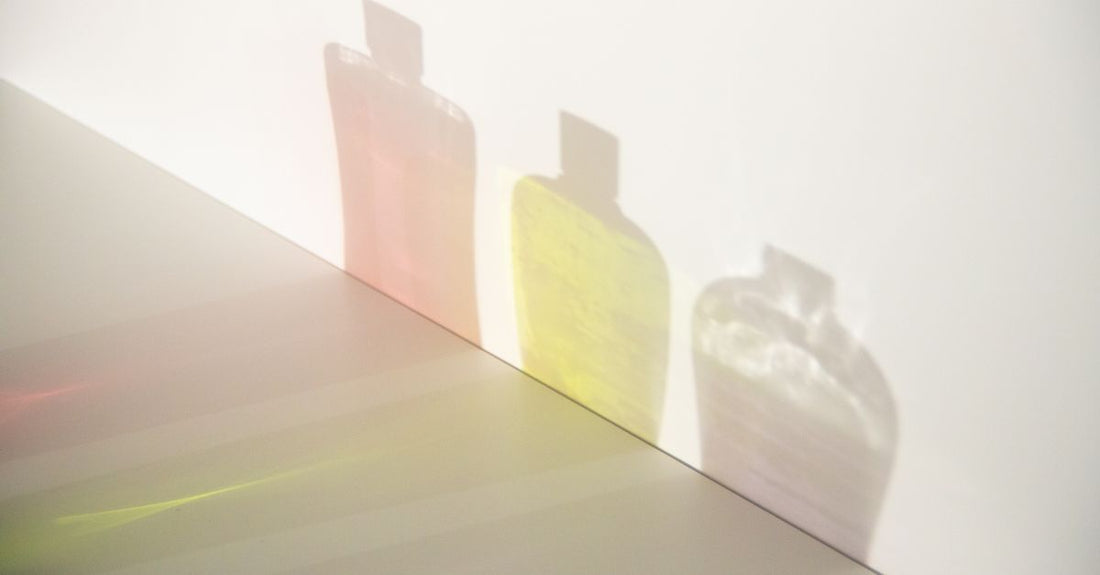 A row of colour-protect shampoo and conditioner bottles on a bathroom shelf, illustrating how to maintain colored hair.