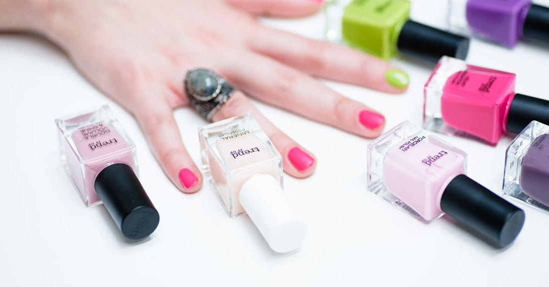 A flatlay of six nail polish bottles in the best summer 2026 colours, arranged on a white marble surface.