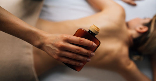 A collection of body oil bottles arranged on a marble surface, representing how to use body oil for glowing skin.