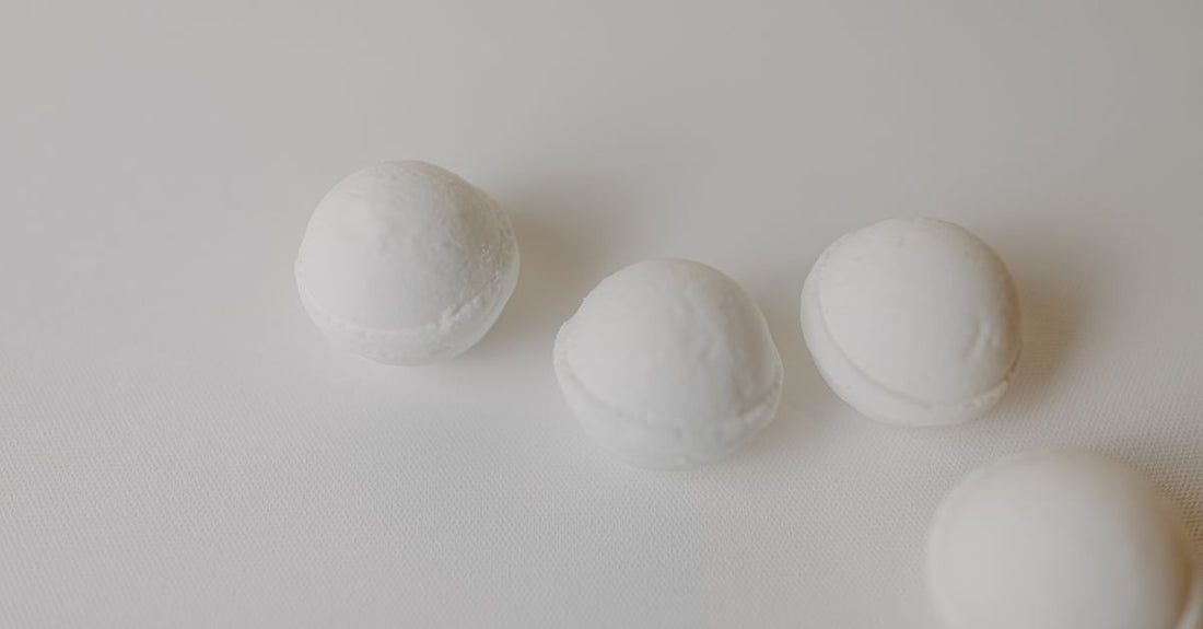 A flatlay of colourful, handmade bath bombs on a white marble surface, representing the best bath bombs 2026 for a relaxing soak.