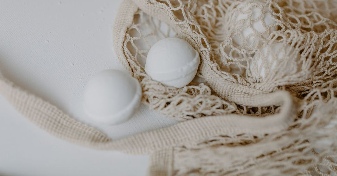 Assorted colourful mesh bath sponges and natural loofahs arranged on a bathroom shelf, illustrating a bath sponges buying guide