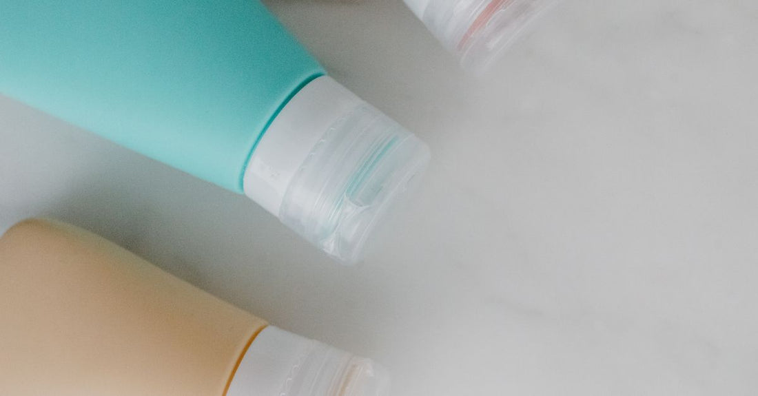 A selection of hand cream tubes and lotion bottles arranged on a marble surface, illustrating a hand creams & lotions buying guide UK.