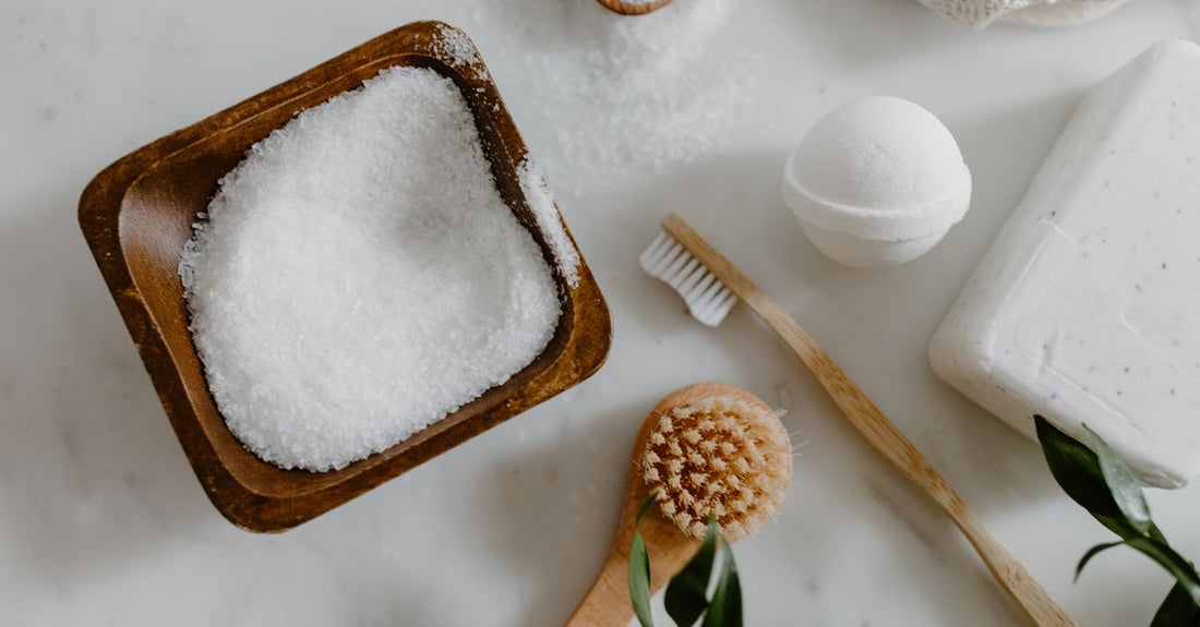 A flatlay of natural bath bomb ingredients including dried flowers, shea butter chunks, and bicarbonate of soda, illustrating a bath bombs buying guide.
