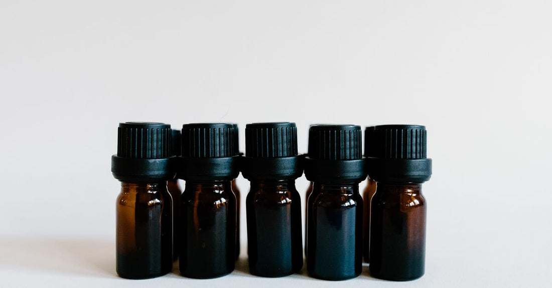 A selection of glass bottles containing different carrier oils, arranged on a neutral surface, illustrating how to choose carrier oils for skincare.